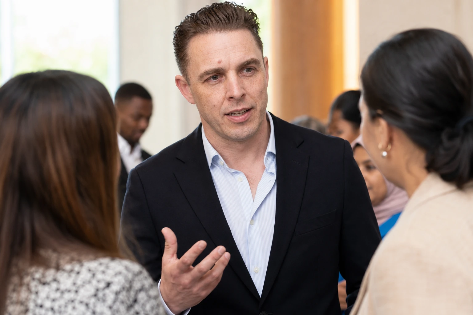 Audrius Cerkasovas speaking with a culturally diverse professional group at an event.